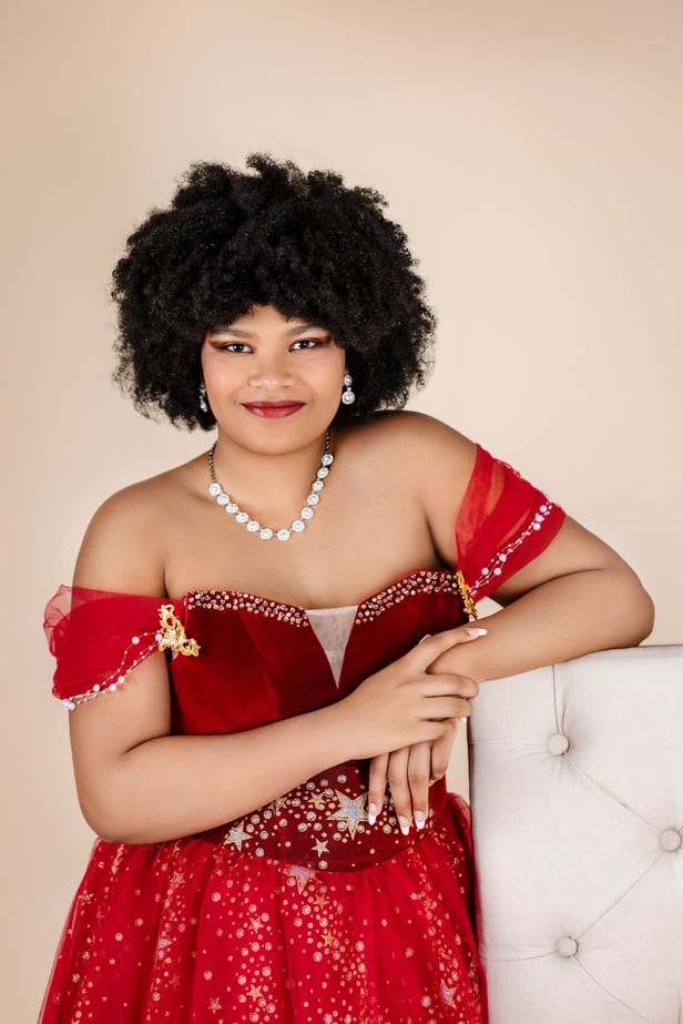 high school Senior Girl in red dress leaning over a chair at the studio