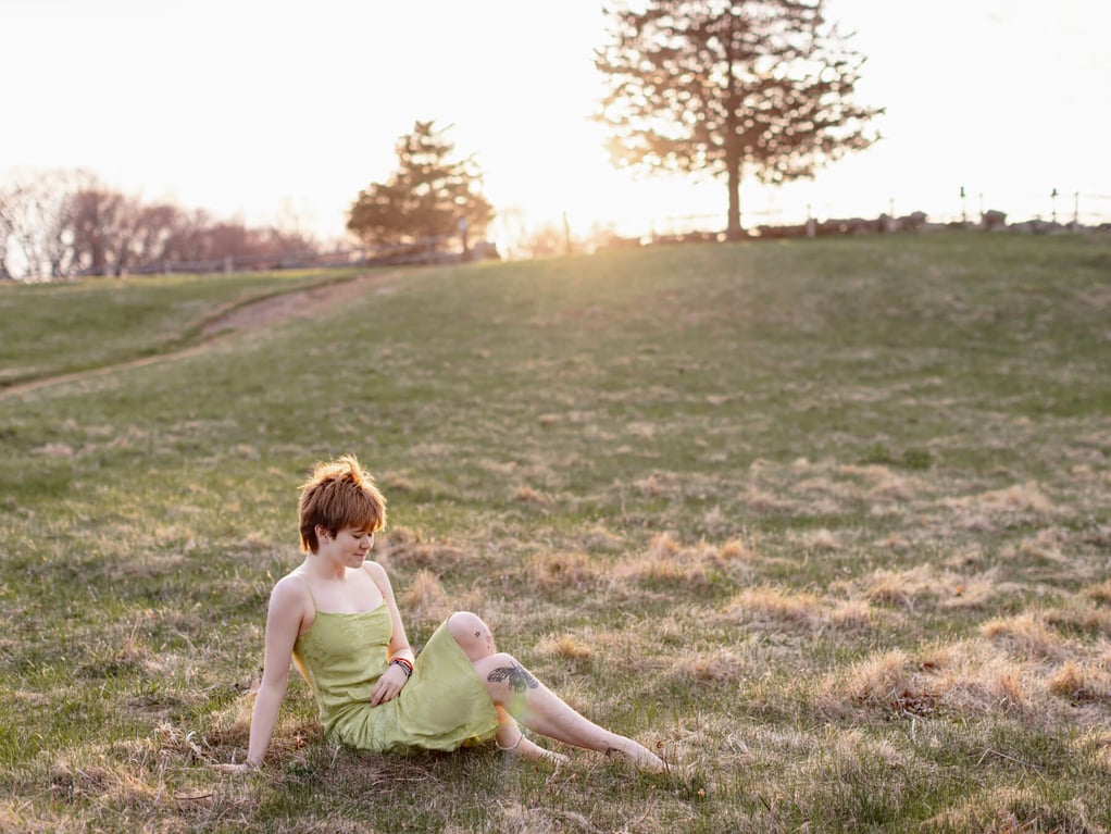 high school senior sitting in the grass at Chiesa Farm in Lexington MA