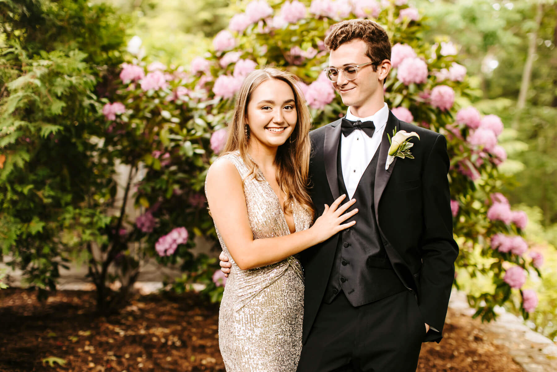 High school senior girl holding her boyfriend, with a green and pink  flower trees as background, at Lexington, Massachusetts