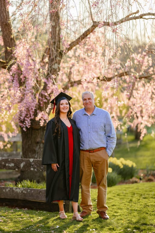 High school senior girl holding her Dad with a pink flower tree as background, at Lexington, Massachusetts