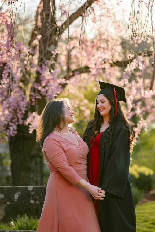 High school senior girl wit cap & gown with Mom. Pink flower tree as background, at Lexington, Massachusetts