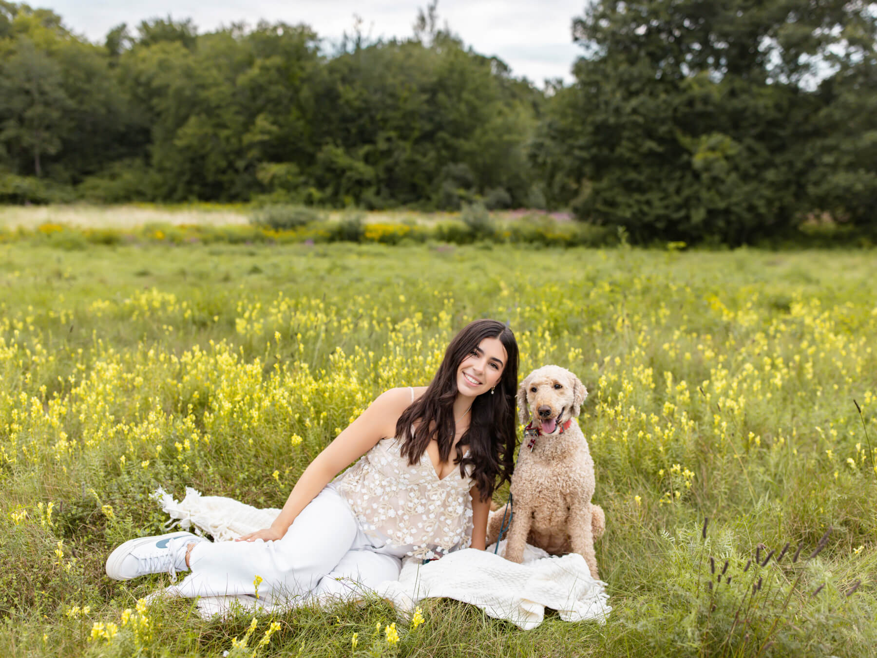 High School senior girl sitting with dog on the yellow field, at Lexington, MA
