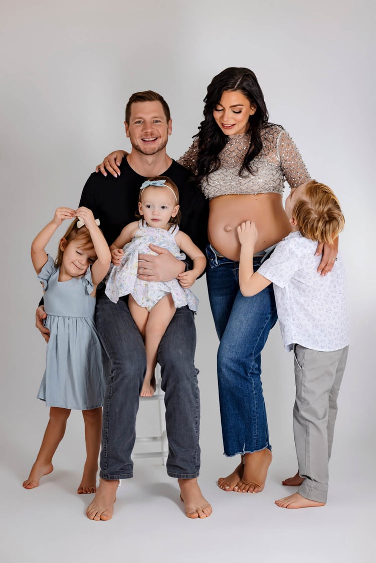 maternity studio portraits, dad sitting down and pregnant mom standing up