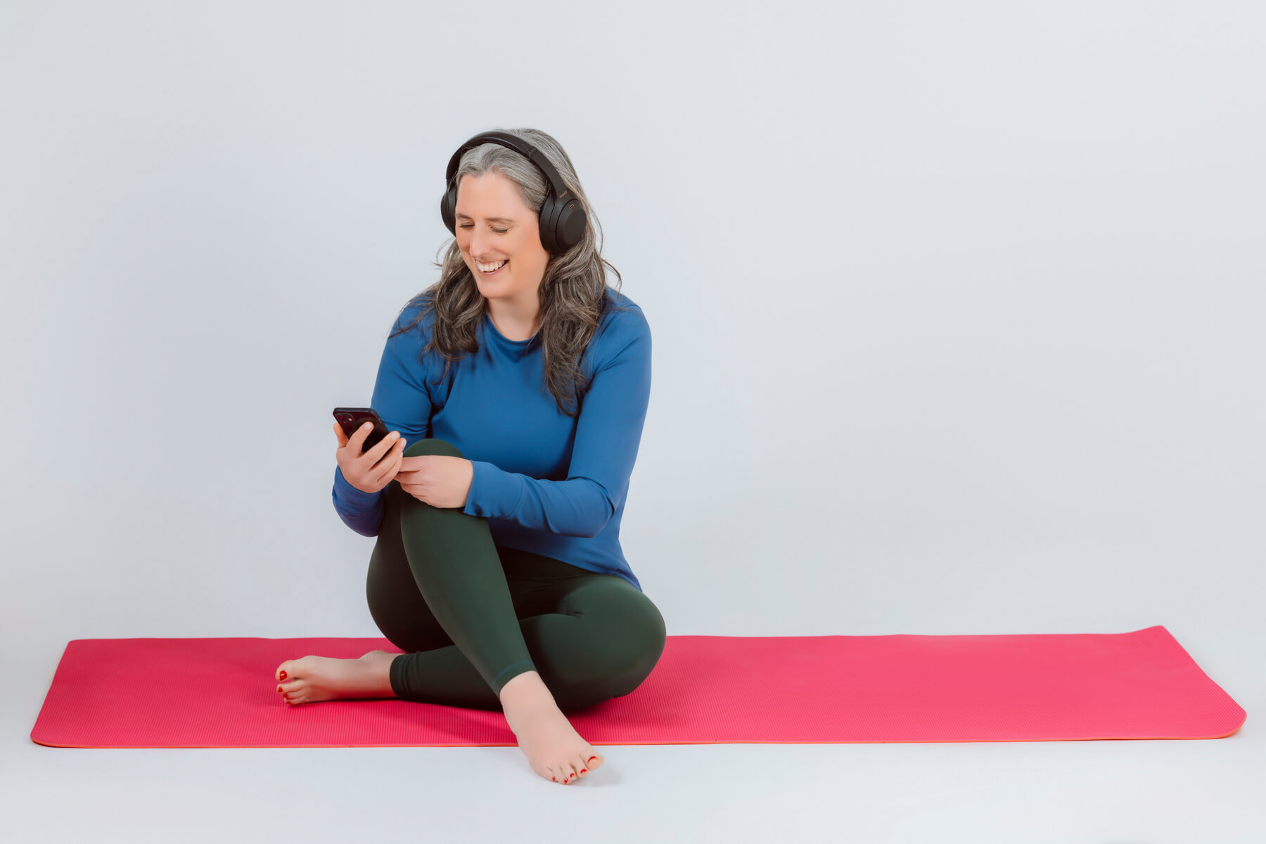 personal branding headshot of a woman sitting in a yoga matt wearing headphones
